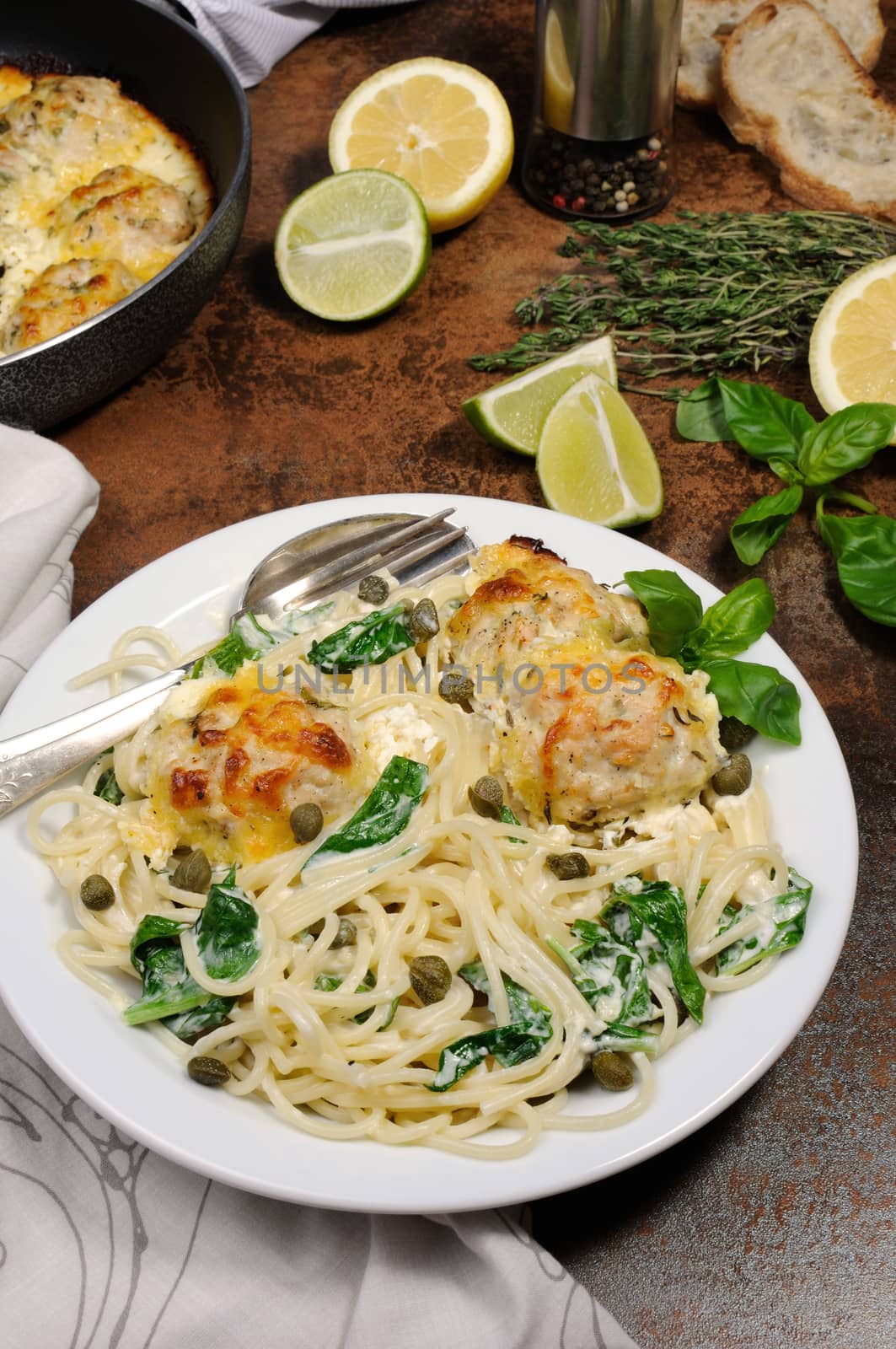 Spaghetti with chicken meatballs in cheese cream sauce , spinach and capers