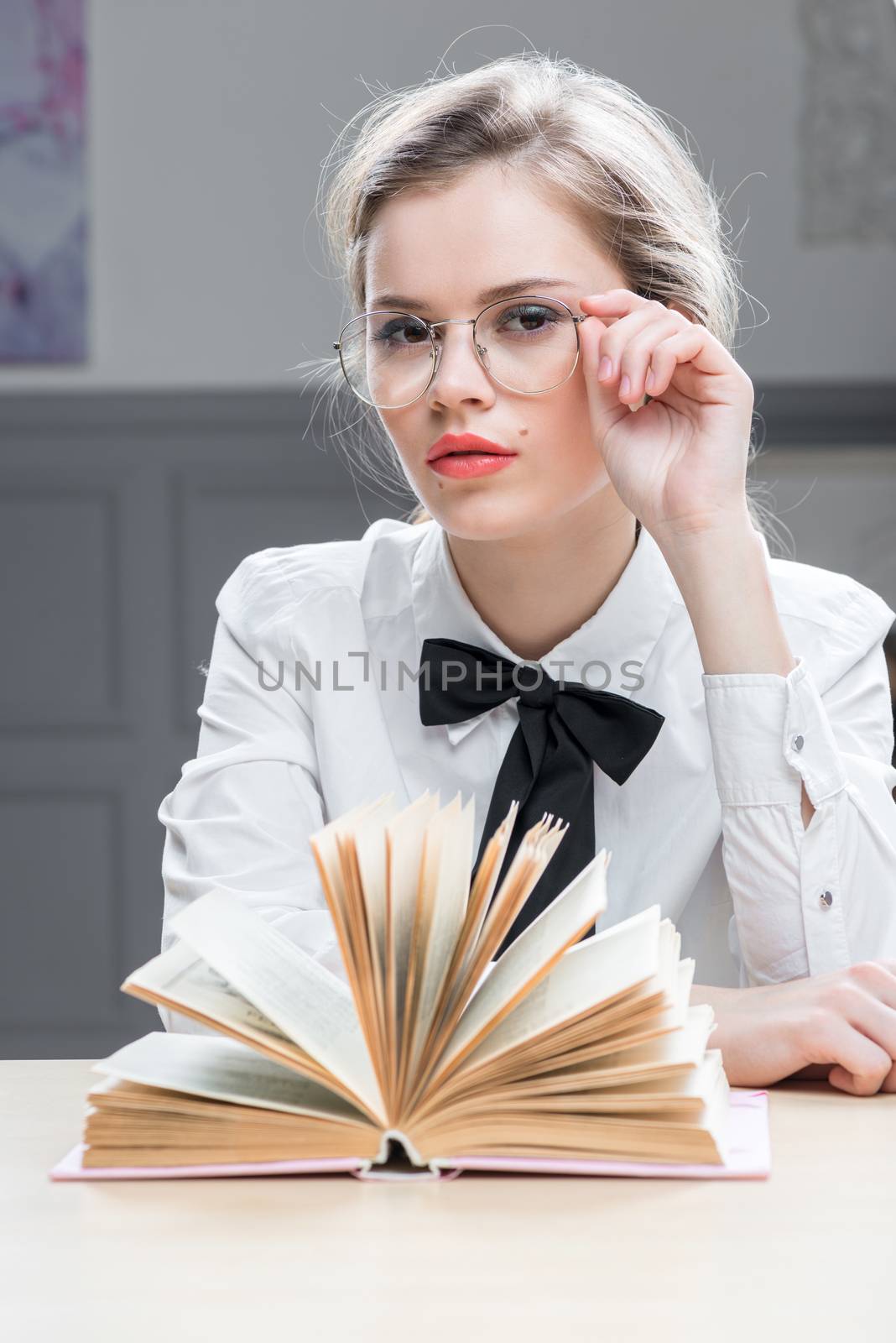 charming successful girl in glasses with a book at the table sit by kosmsos111