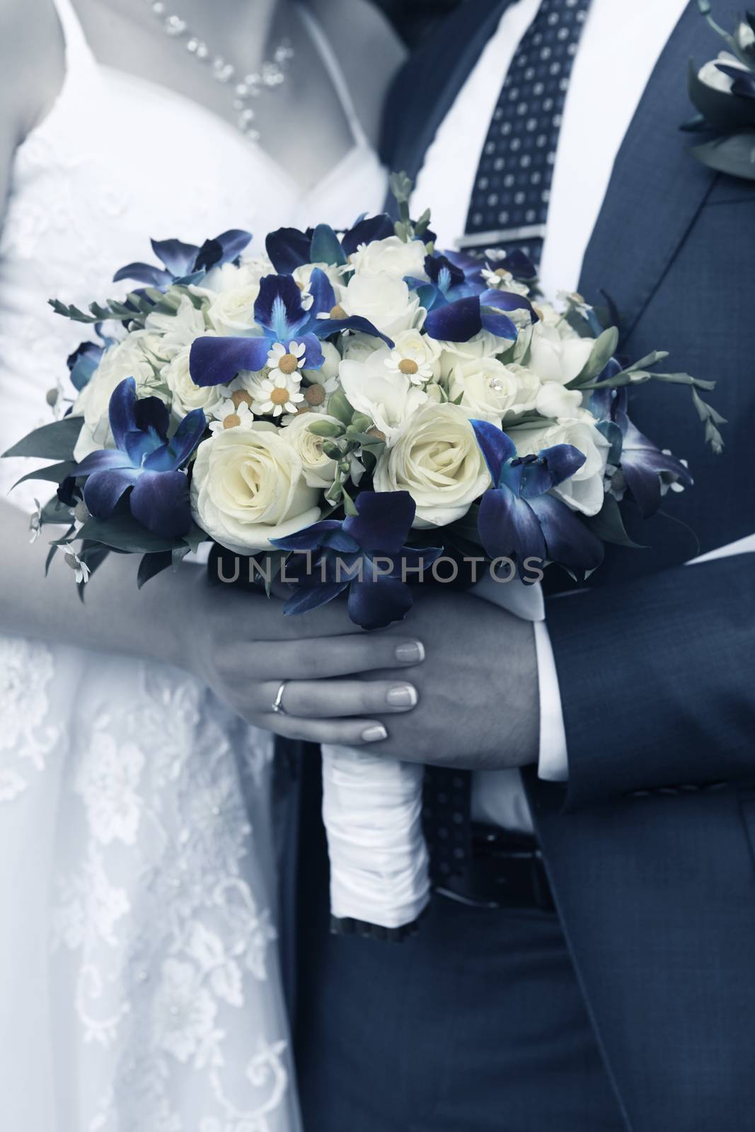 Hand of the groom and the bride with wedding bouquet