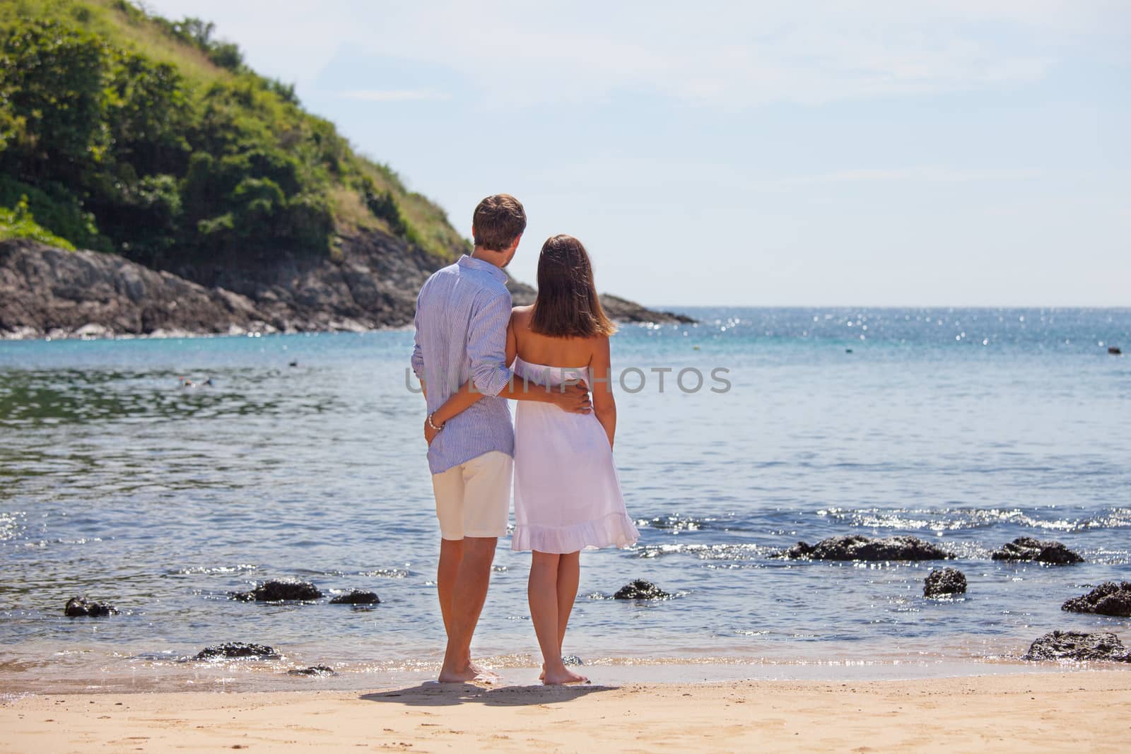 Young couple on beach looking at sea together