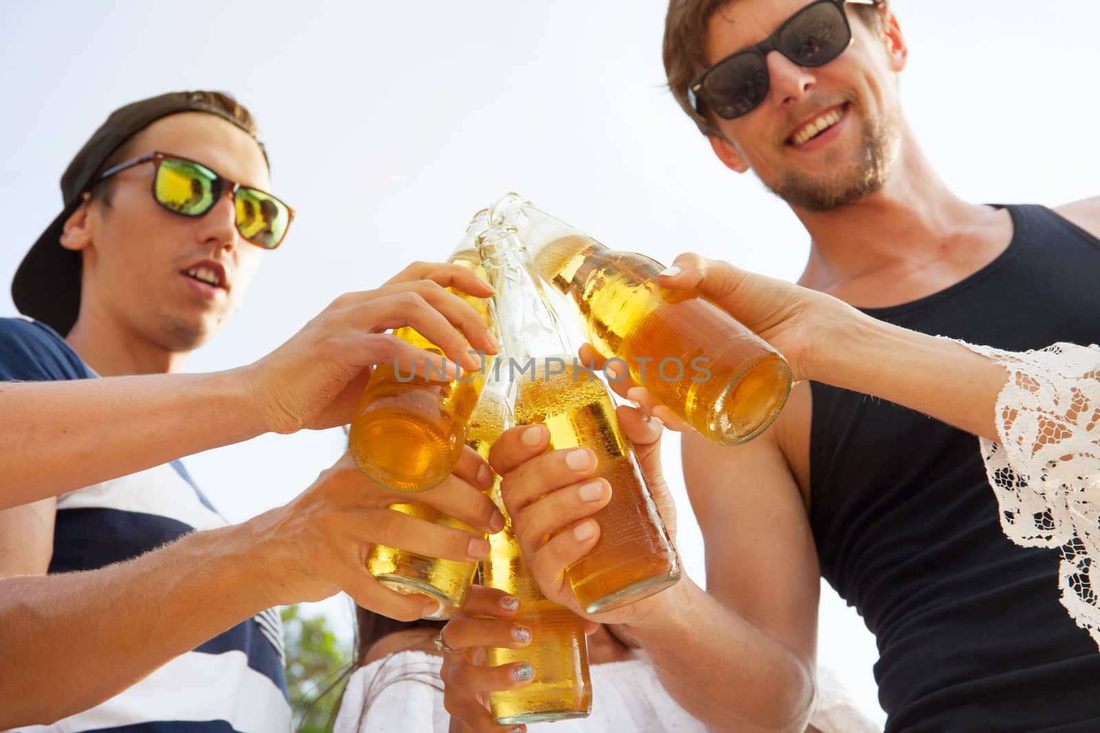 Happy young friends drinking beer outdoors