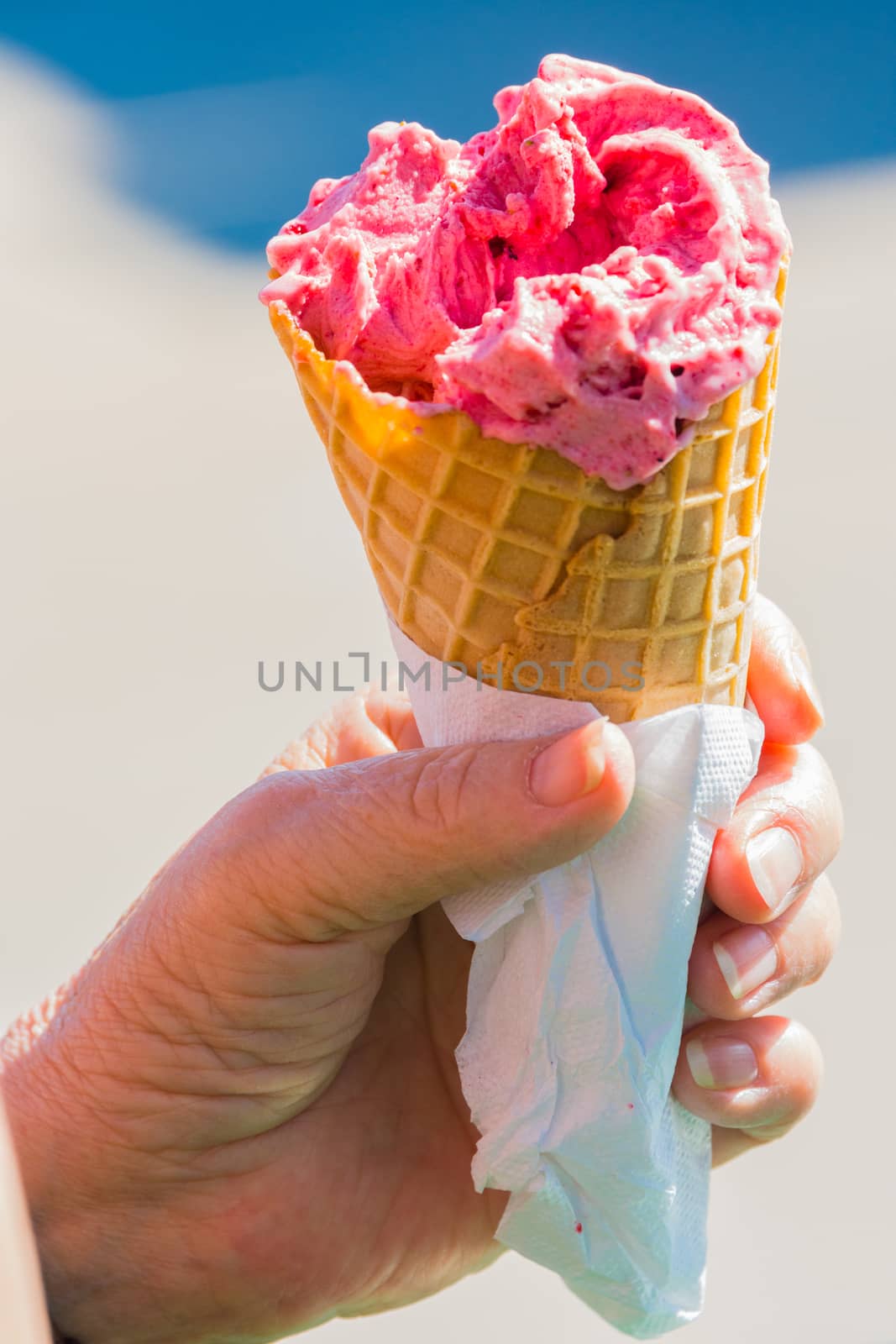 Fruit ice cream in hand in a waffle cup against the sky by ben44