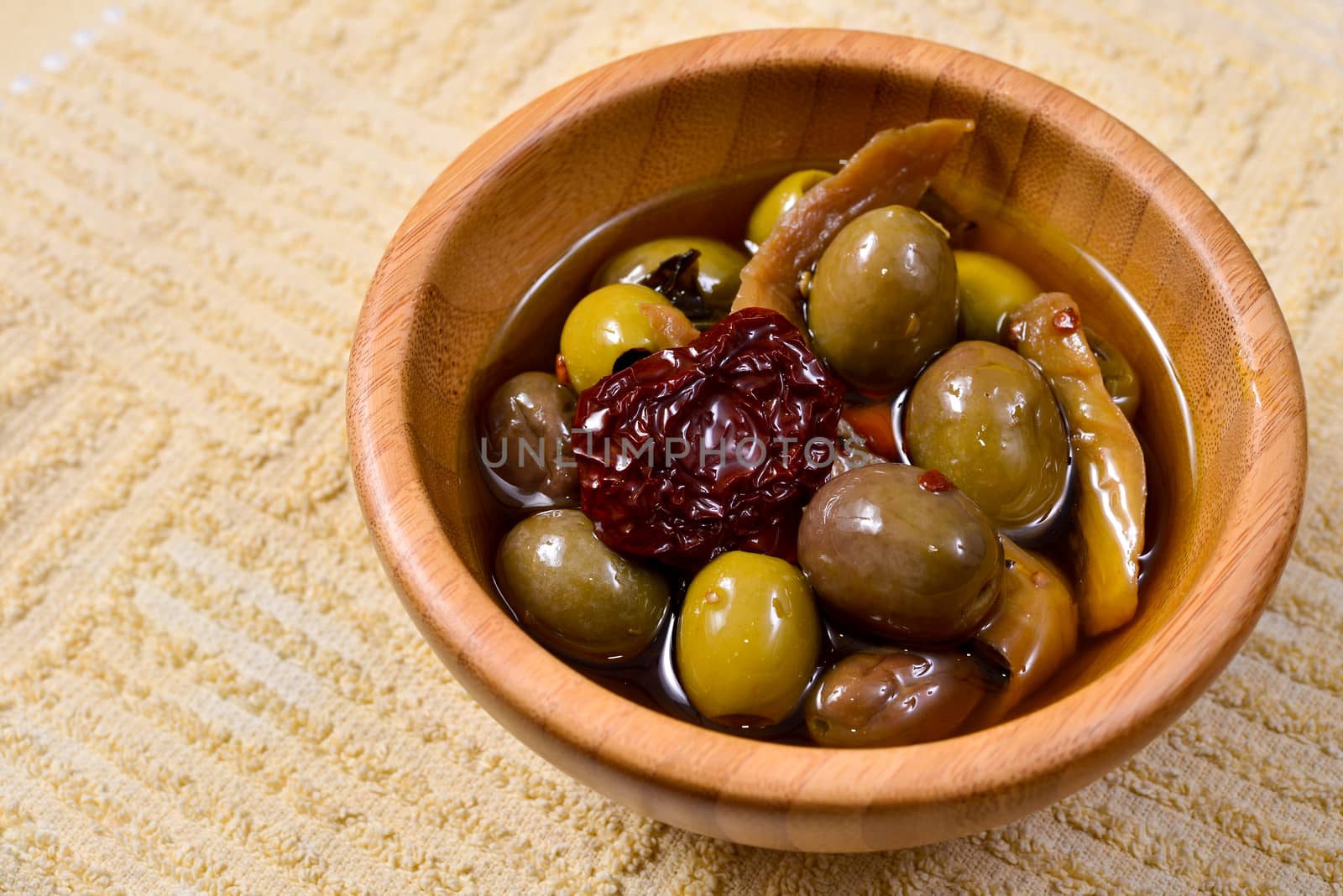 Bowl filled with freshly harvested whole fresh green olives on a wooden tabletop.