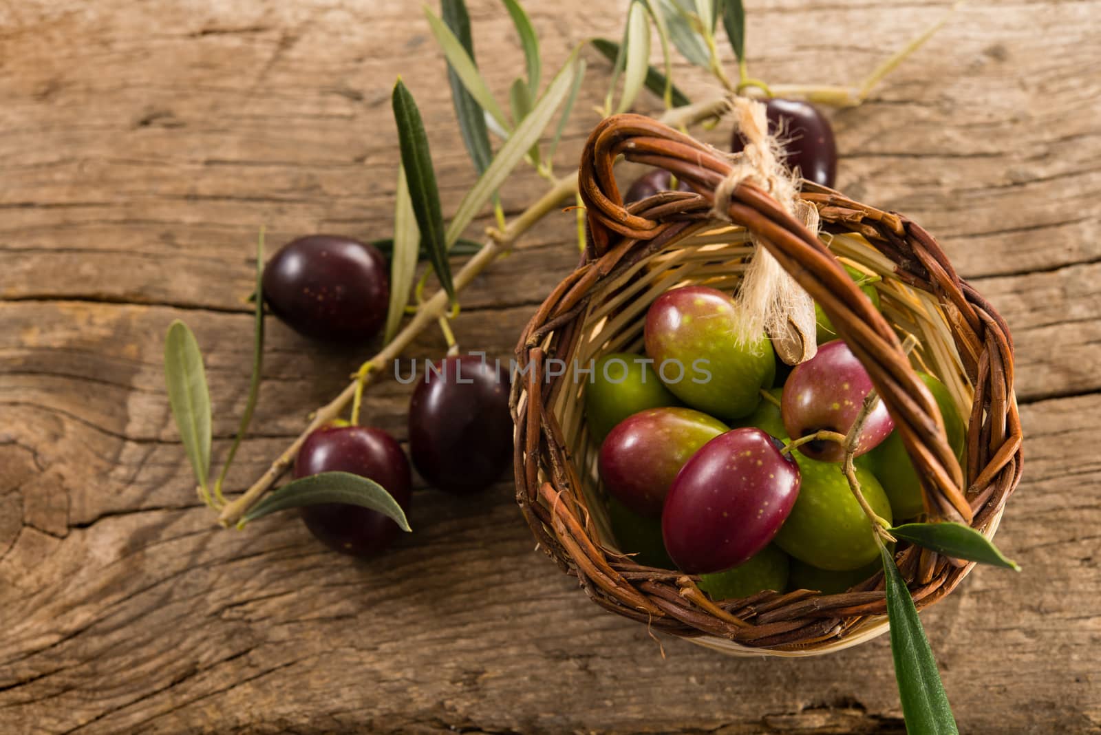 fresh olives in a basket, placed on a rustic wooden table. Olives from Sicily, Italy