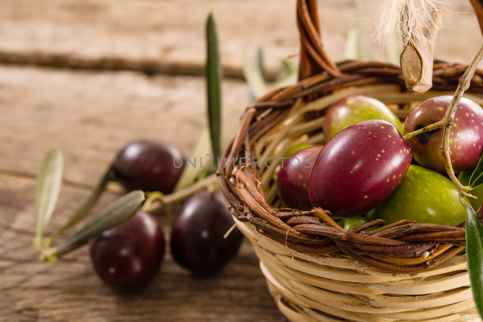 fresh olives in a basket, placed on a rustic wooden table. Olives from Sicily, Italy