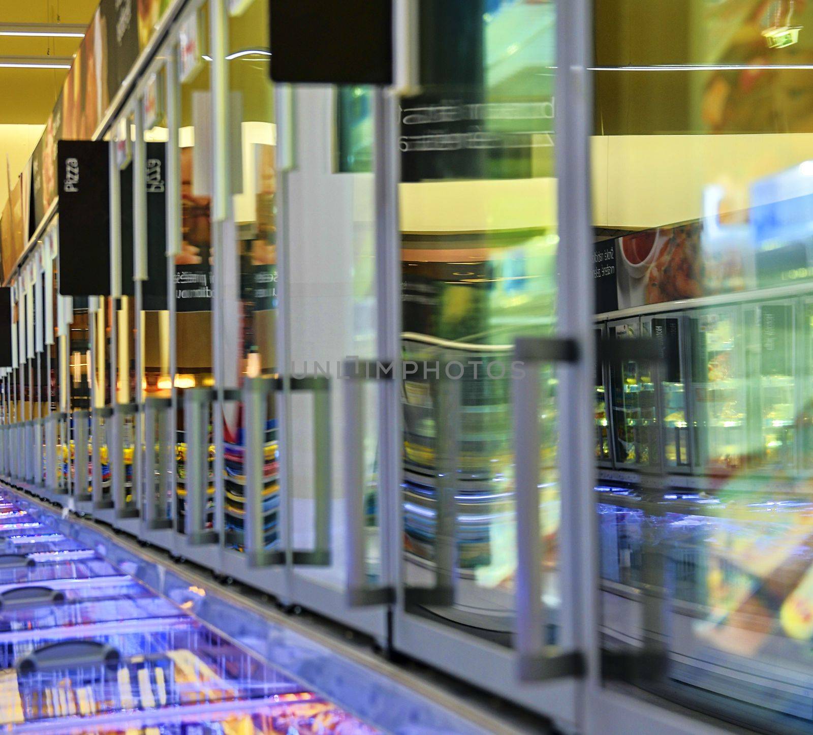 Blurred frozen food section at retail store in Europe.  Freezer full assortment of frozen pizza in local supermarket, defocused background by roman_nerud