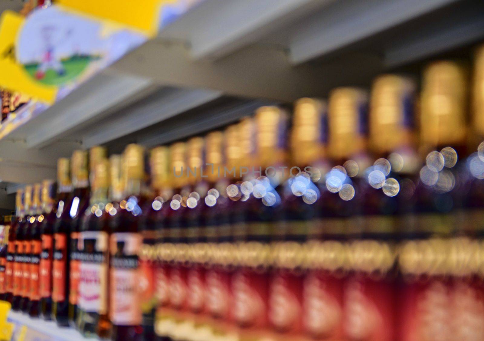 Blurred section bottles of spirit, hard liquor at retail store in Europe. Aisle in local supermarket, defocused background by roman_nerud