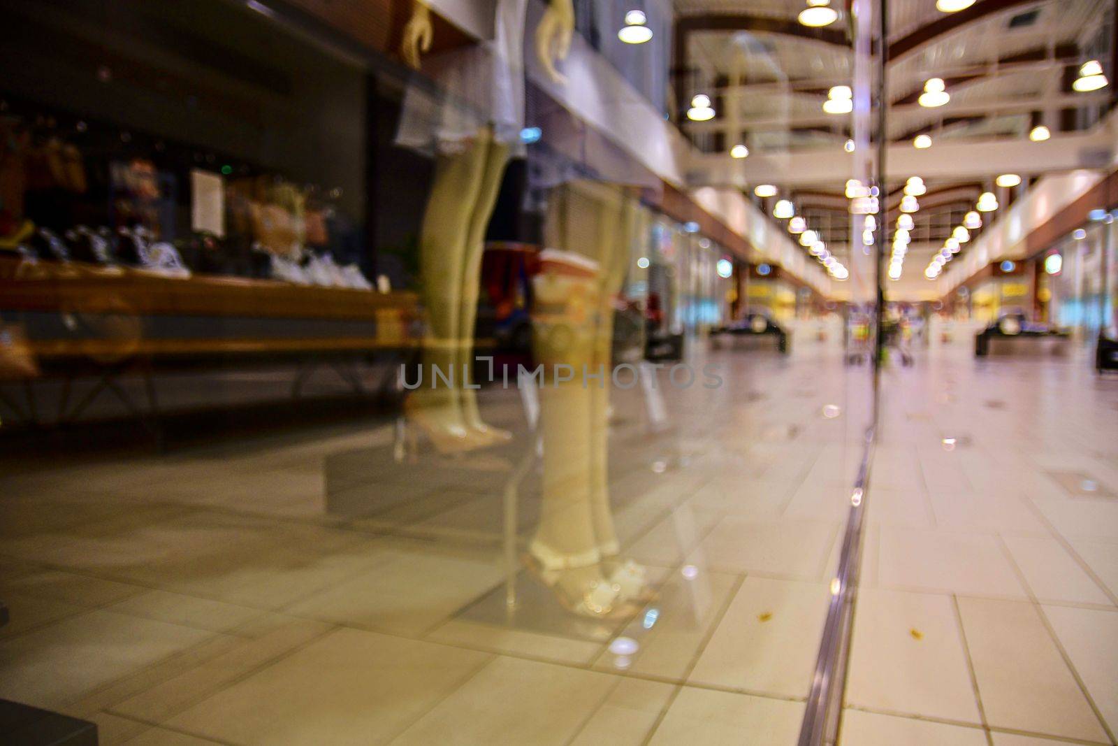 Blurred shop windows at retail store in Europe. Corridor in local supermarket, defocused background. Fashion clothes retail store sale display with female woman mannequin.