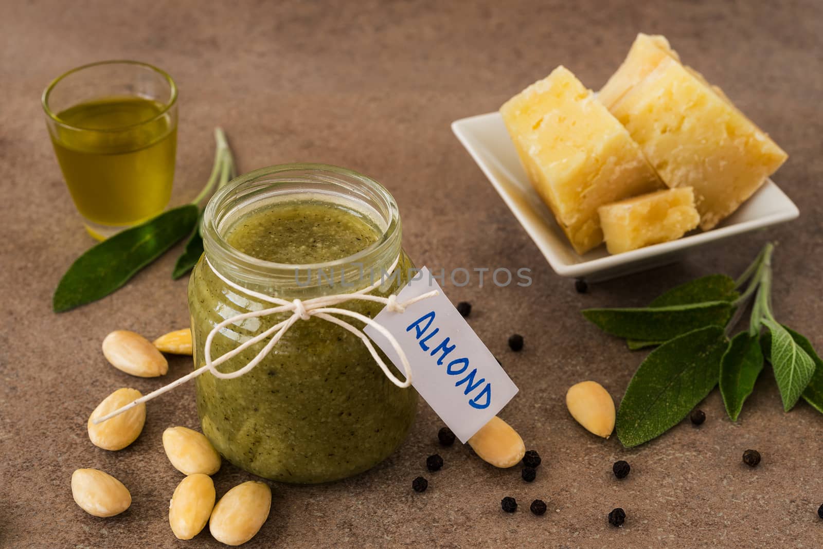 Pesto of almonds and pecorino cheese in a glass jar on a wooden table