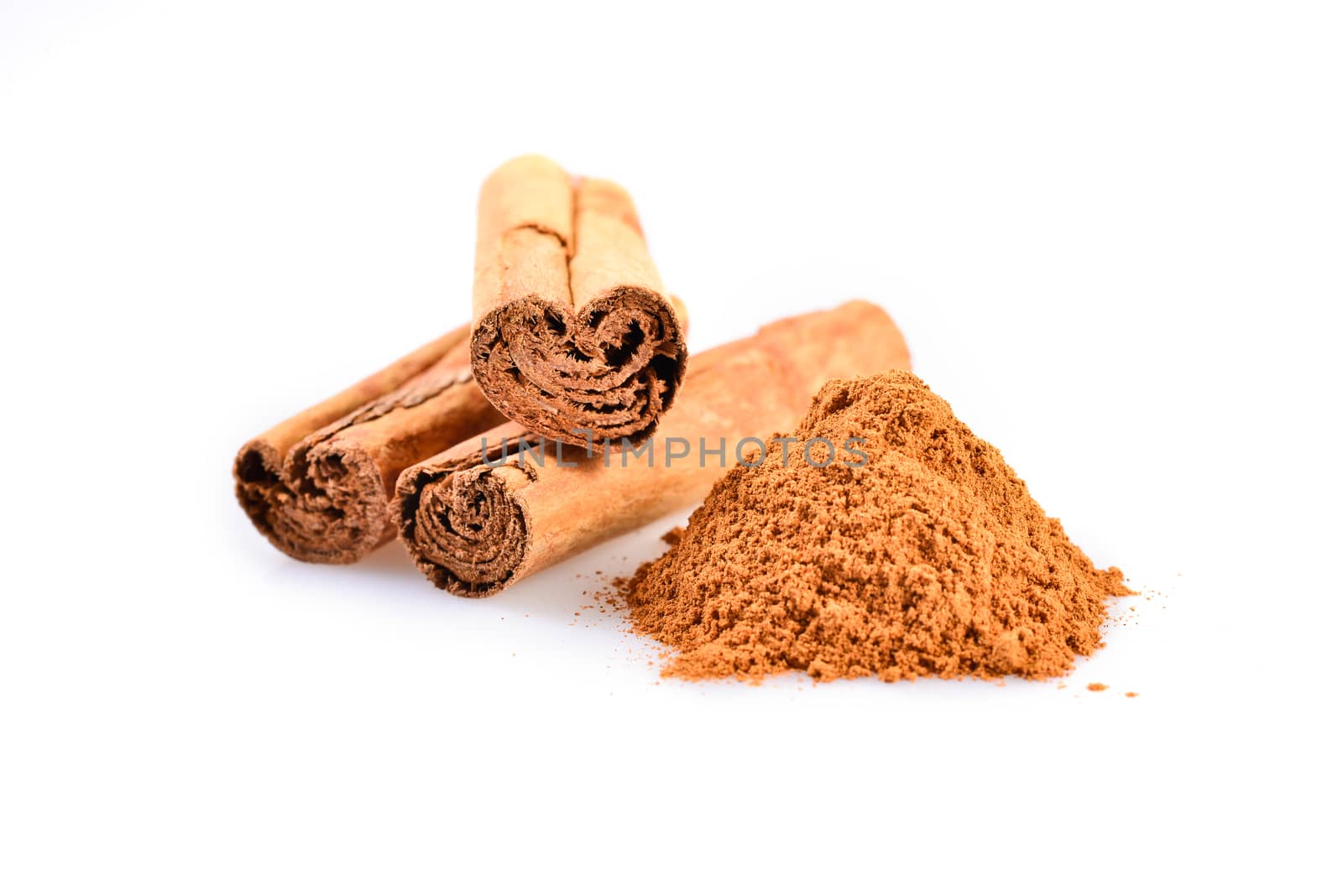 macro photograph of cinnamon sticks dry beside a teaspoon of ground cinnamon
