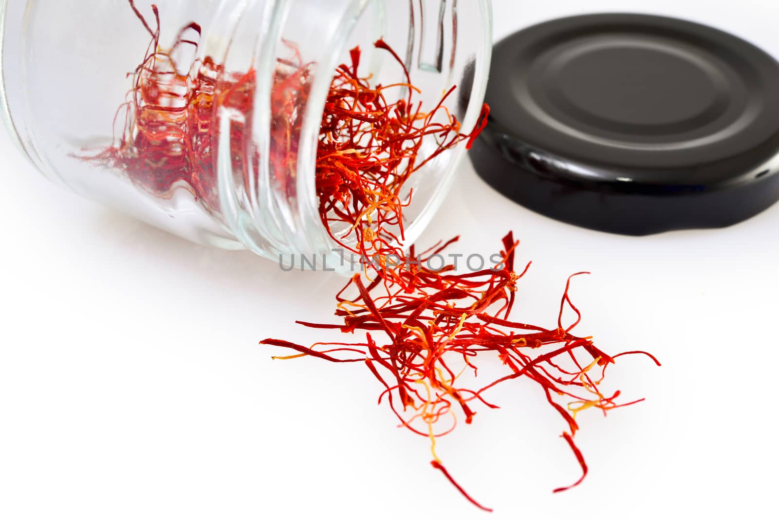 Pistils dried saffron in a glass jar, on a white table