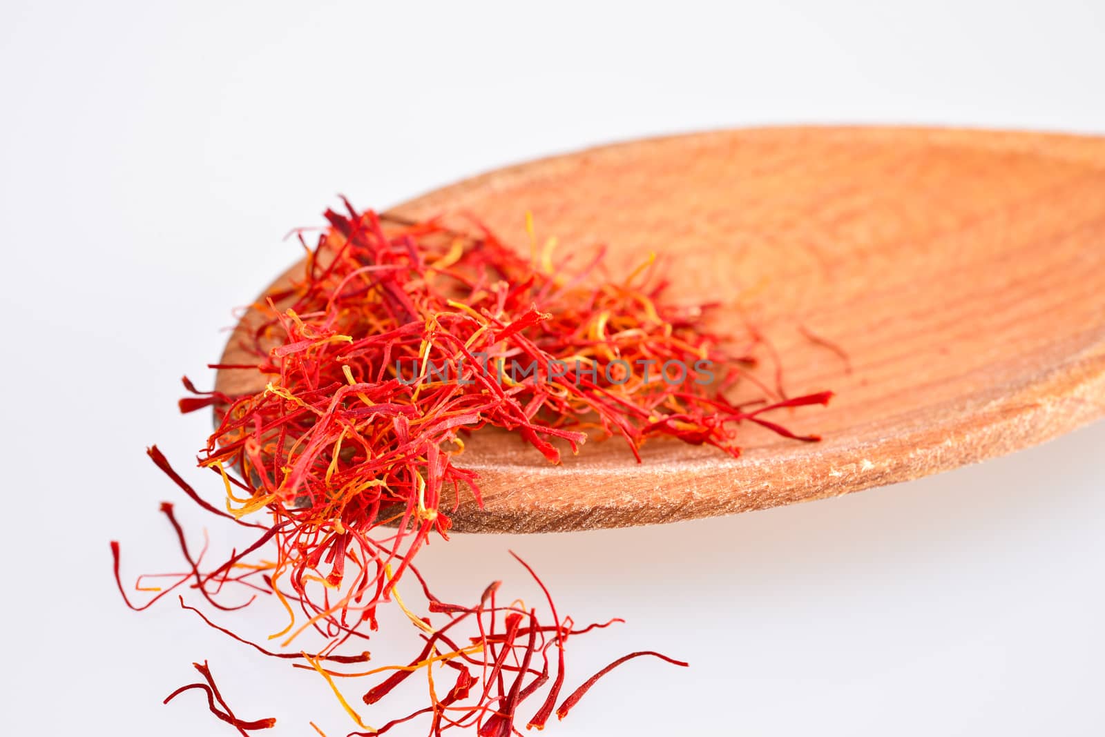 Pistils dried saffron on a wooden spoon, isolated on a white background