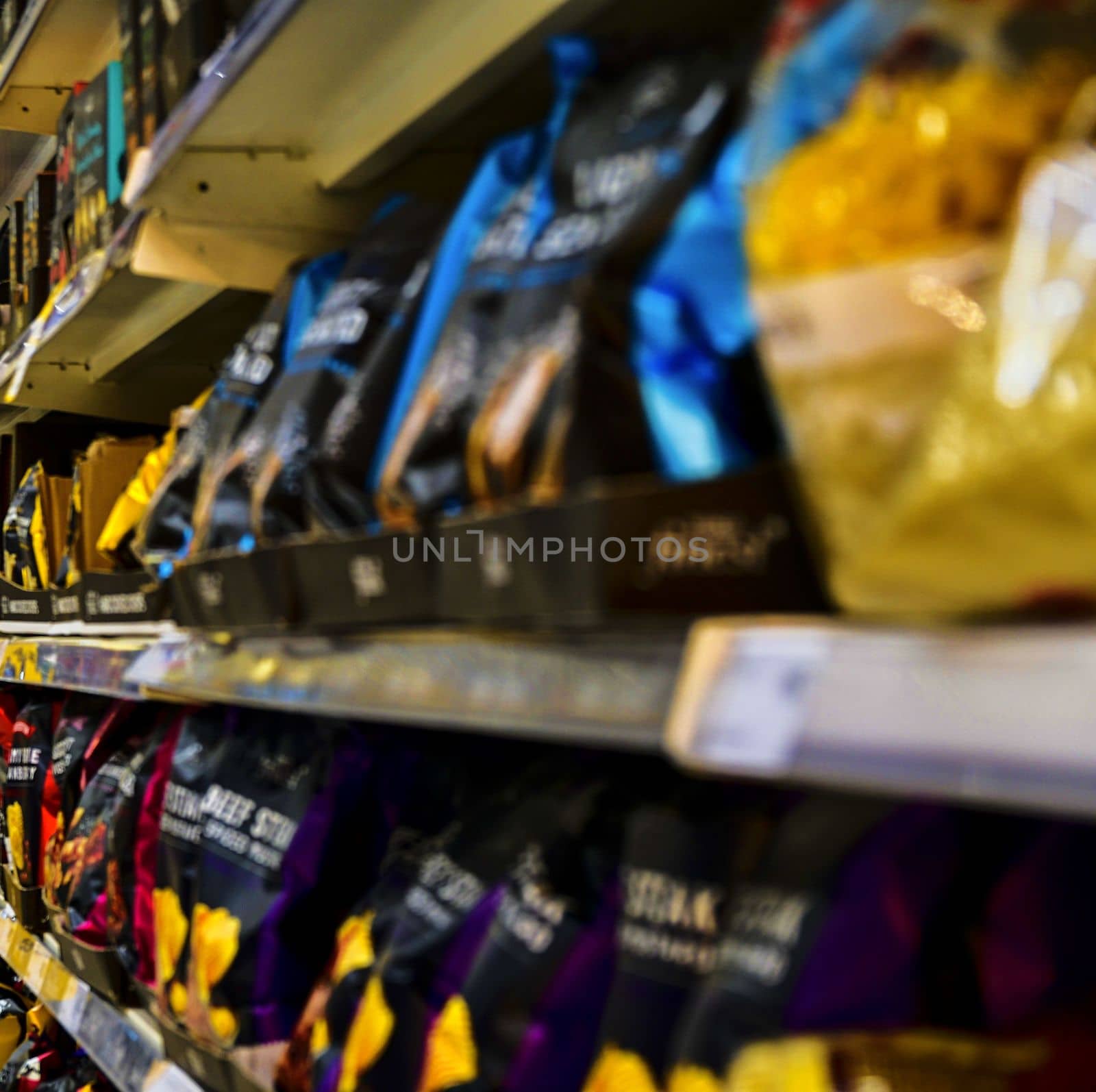 Blurred section spiced chips, spiced crisps  at retail store in Europe.  Aisle in local supermarket, defocused background.