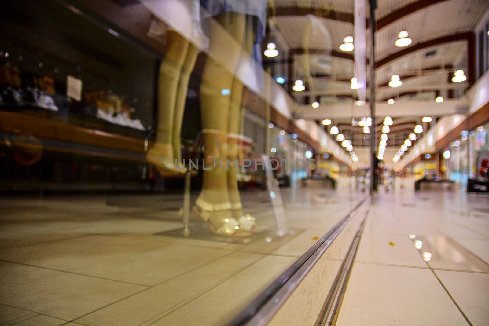 Blurred shop windows at retail store in Europe. Corridor in local supermarket, defocused background. Fashion clothes retail store sale display with female woman mannequin.