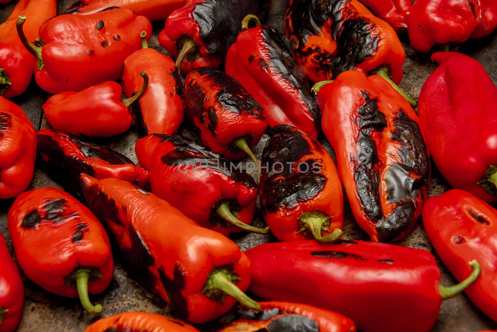 Several red peppers roasting on the stove to be turned into ajvar, a tasty spread popular in the Balkans.
