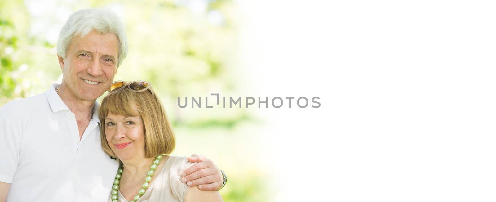 Happy senior couple in love embracing in park, white copy space