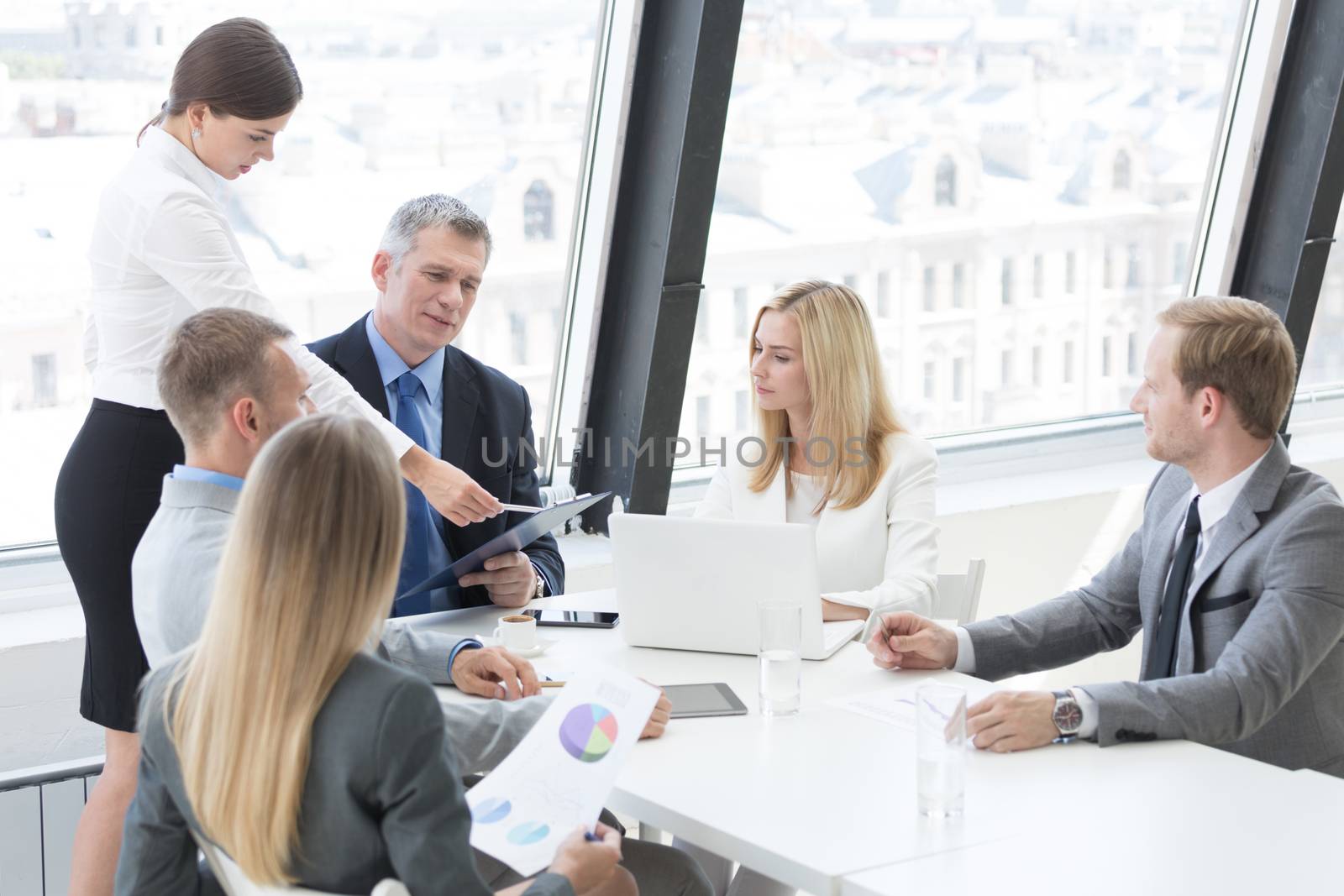 Business person group in formalwear discuss documents at meeting in modern office