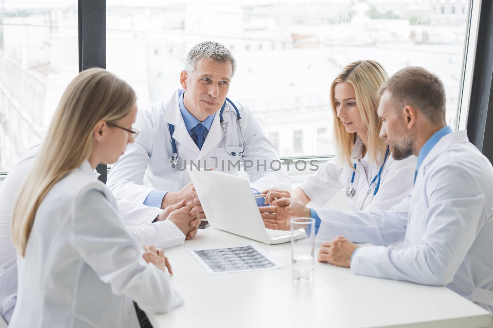 Clinic, people, healthcare and medicine concept - group of medics with brain x-ray scan and laptop at hospital office