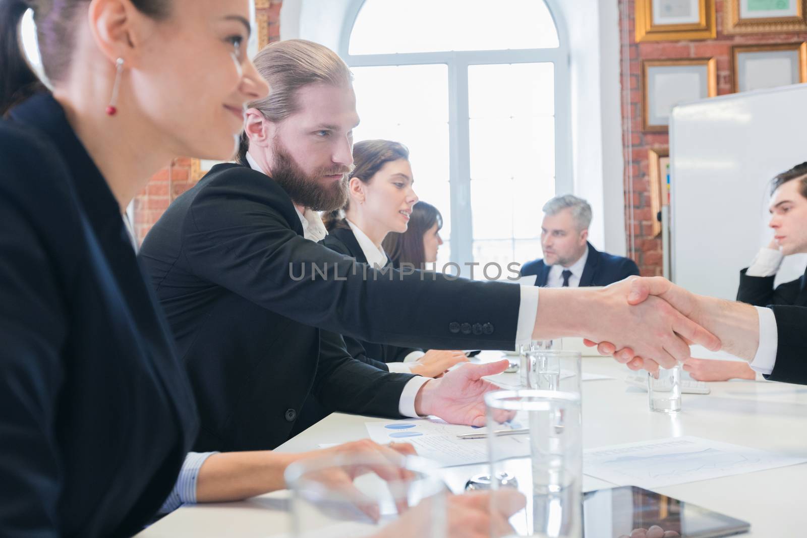 Business people shaking hands at meeting in office after discussion of financial charts