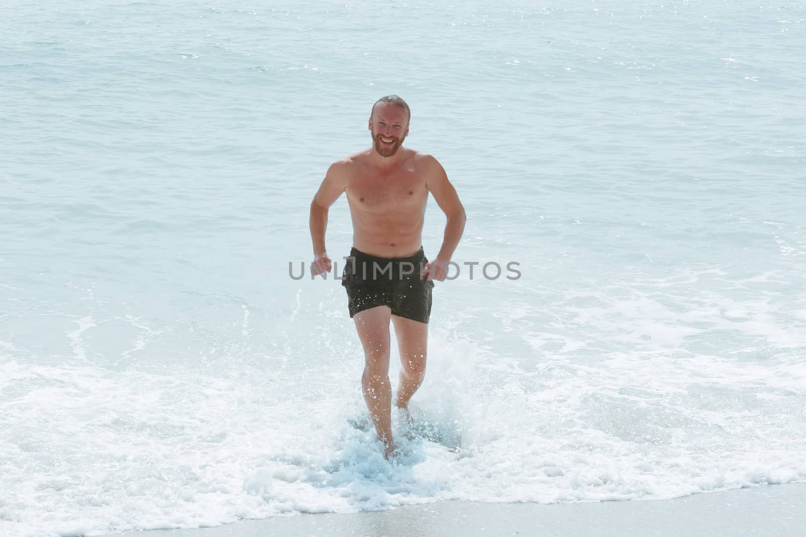 Happy man running from sea by destillat