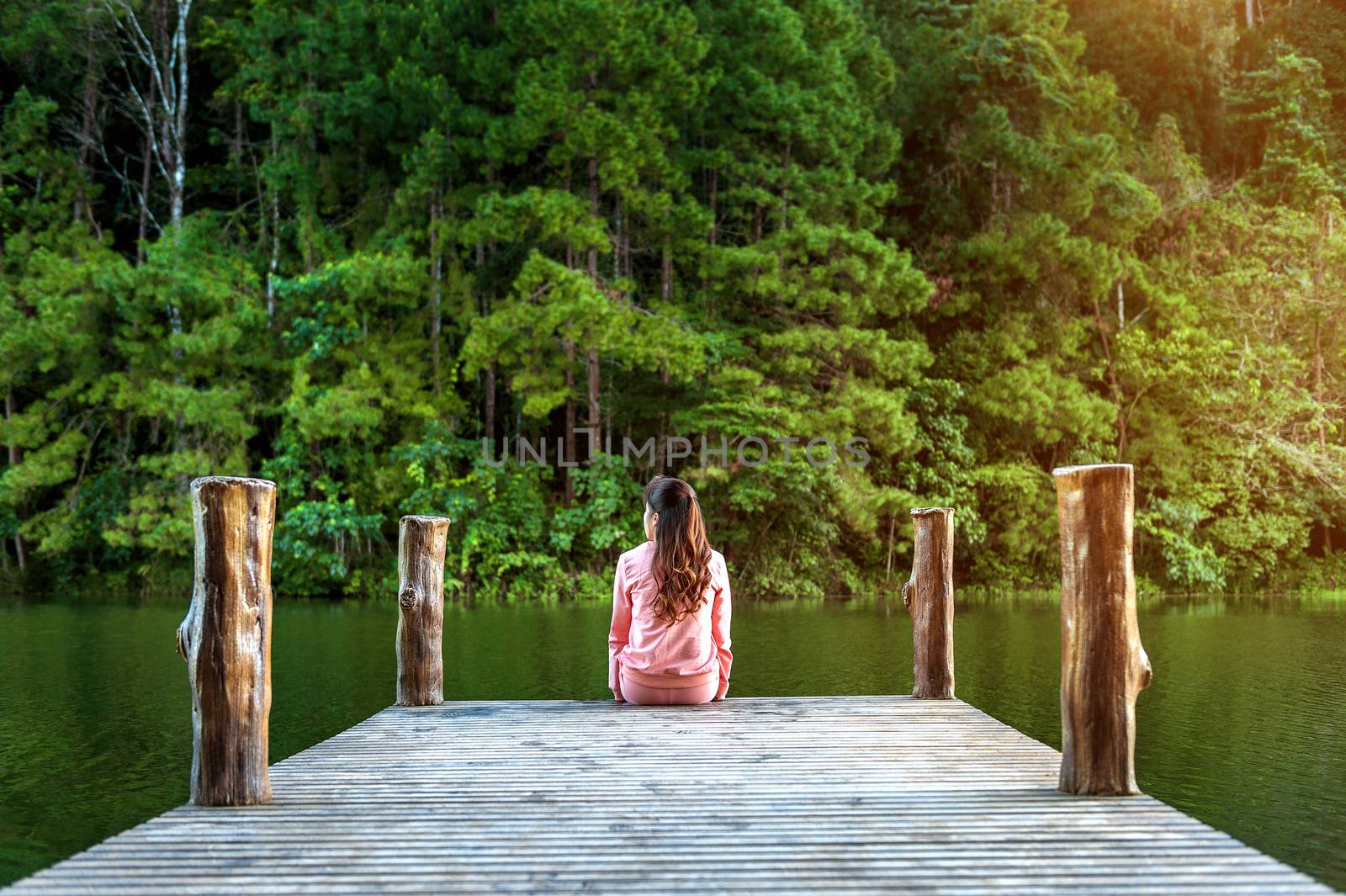 Girl sitting alone on a the wooden bridge on the lake. Pang Ung, Thailand. by gutarphotoghaphy
