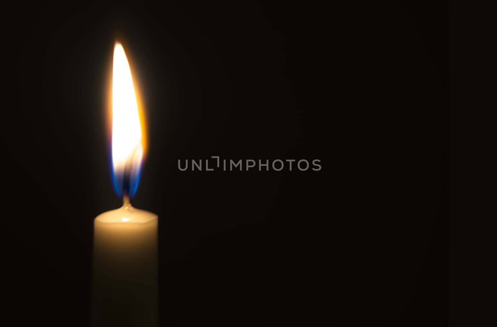 One light candle burning brightly in the black background by hongee