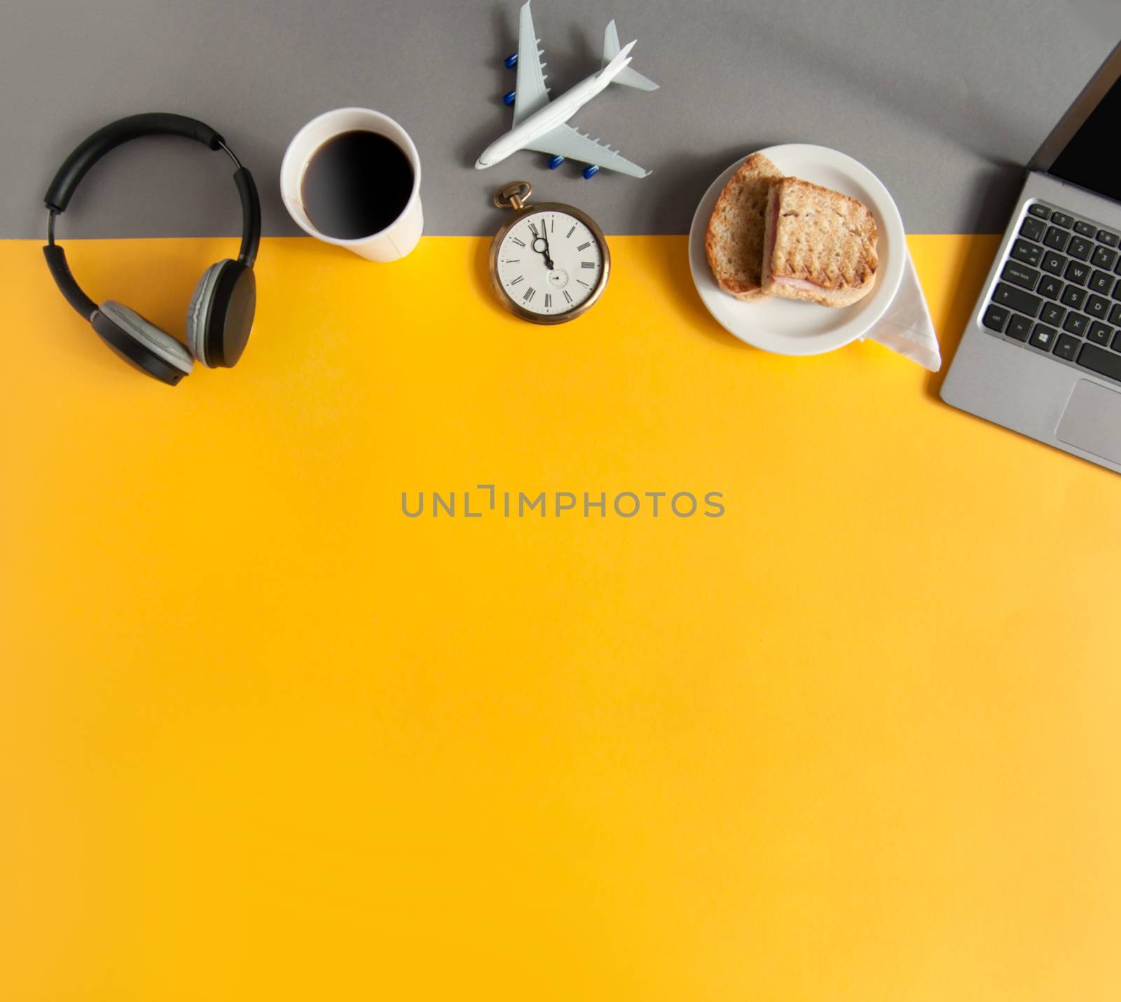 Business accessories including laptop, clock with grilled sandwich view from above