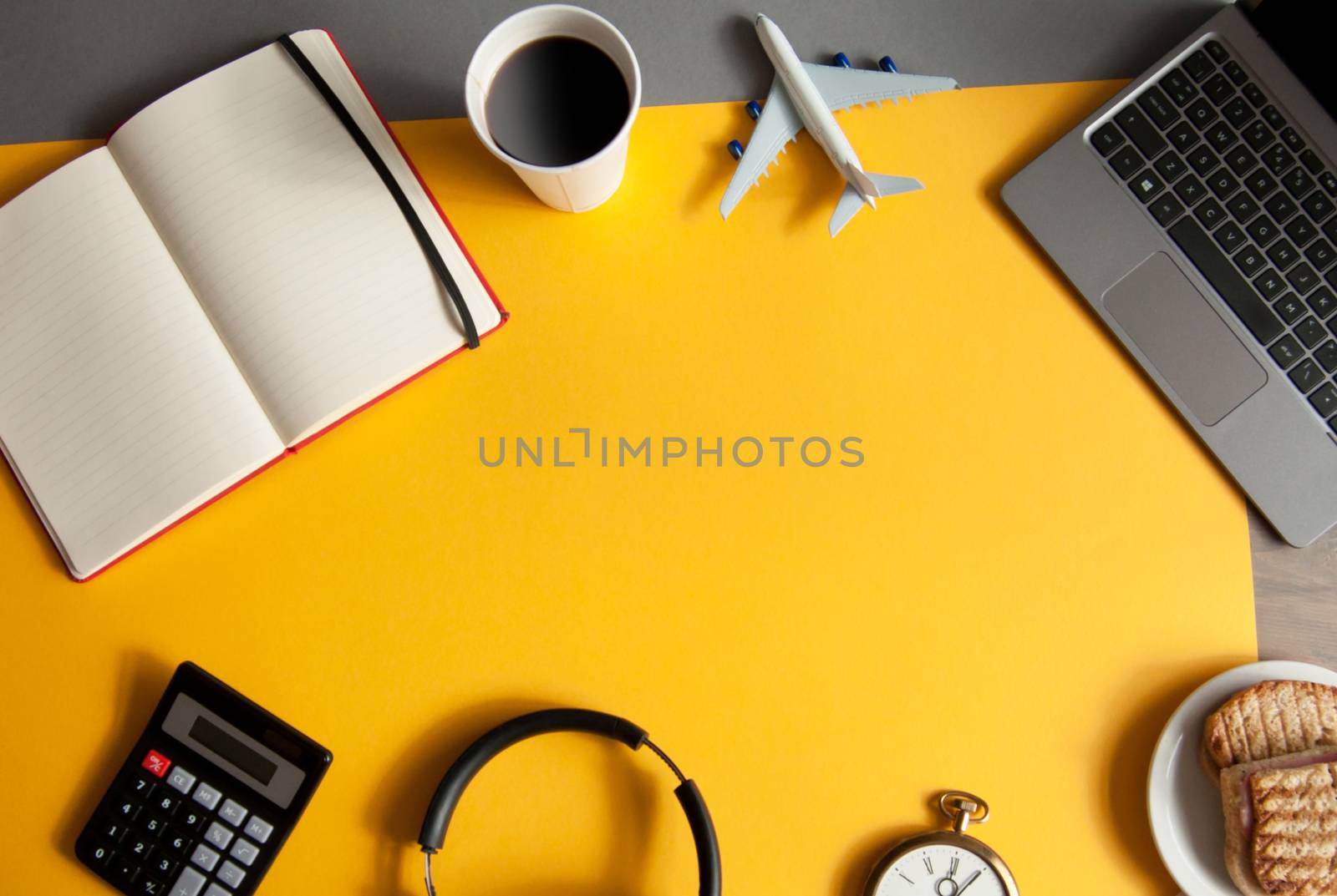 Laptop with miniature plane, clock and coffee, view from above