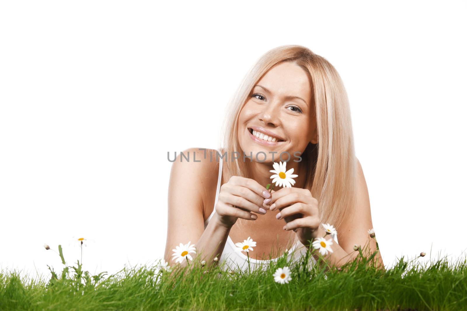 Beautiful young blonde woman lying on grass with chamomile flowers, isolated on white background