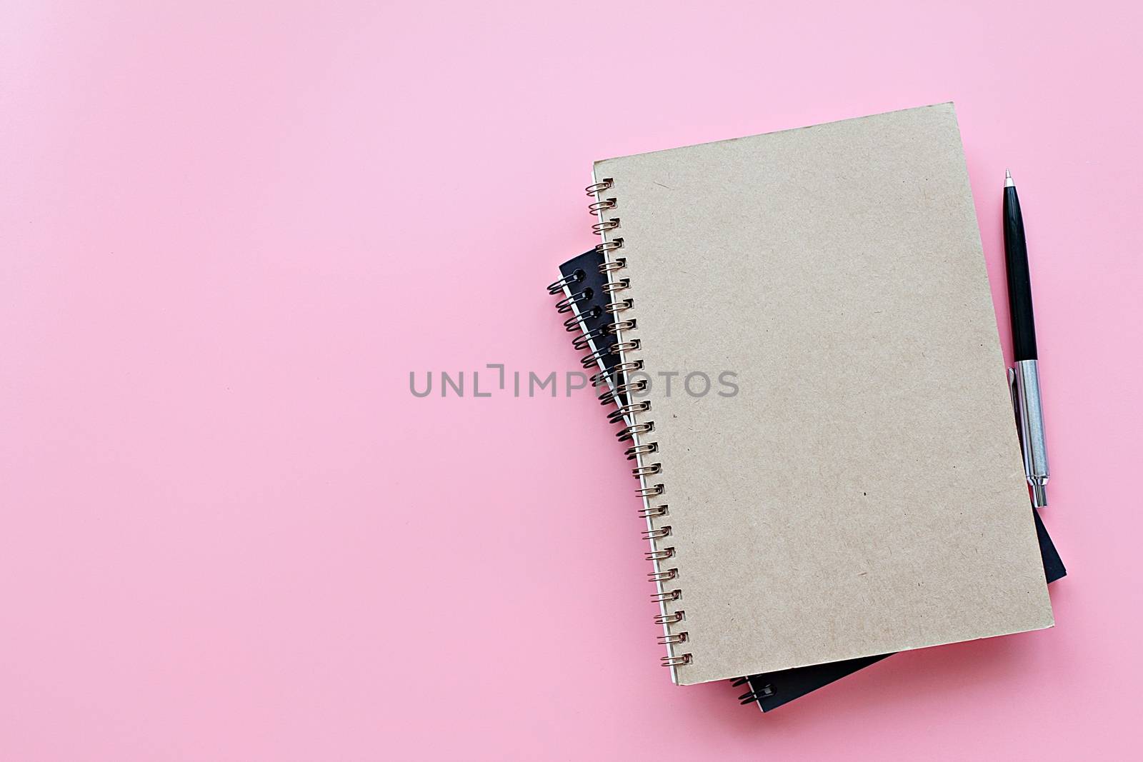 Top view or flat lay of notebooks and pen on pink background by sureeporn