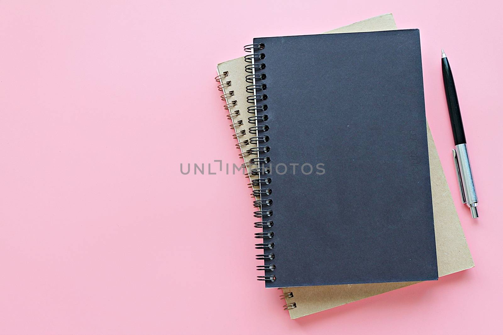 Top view or flat lay of notebooks and pen on pink background by sureeporn