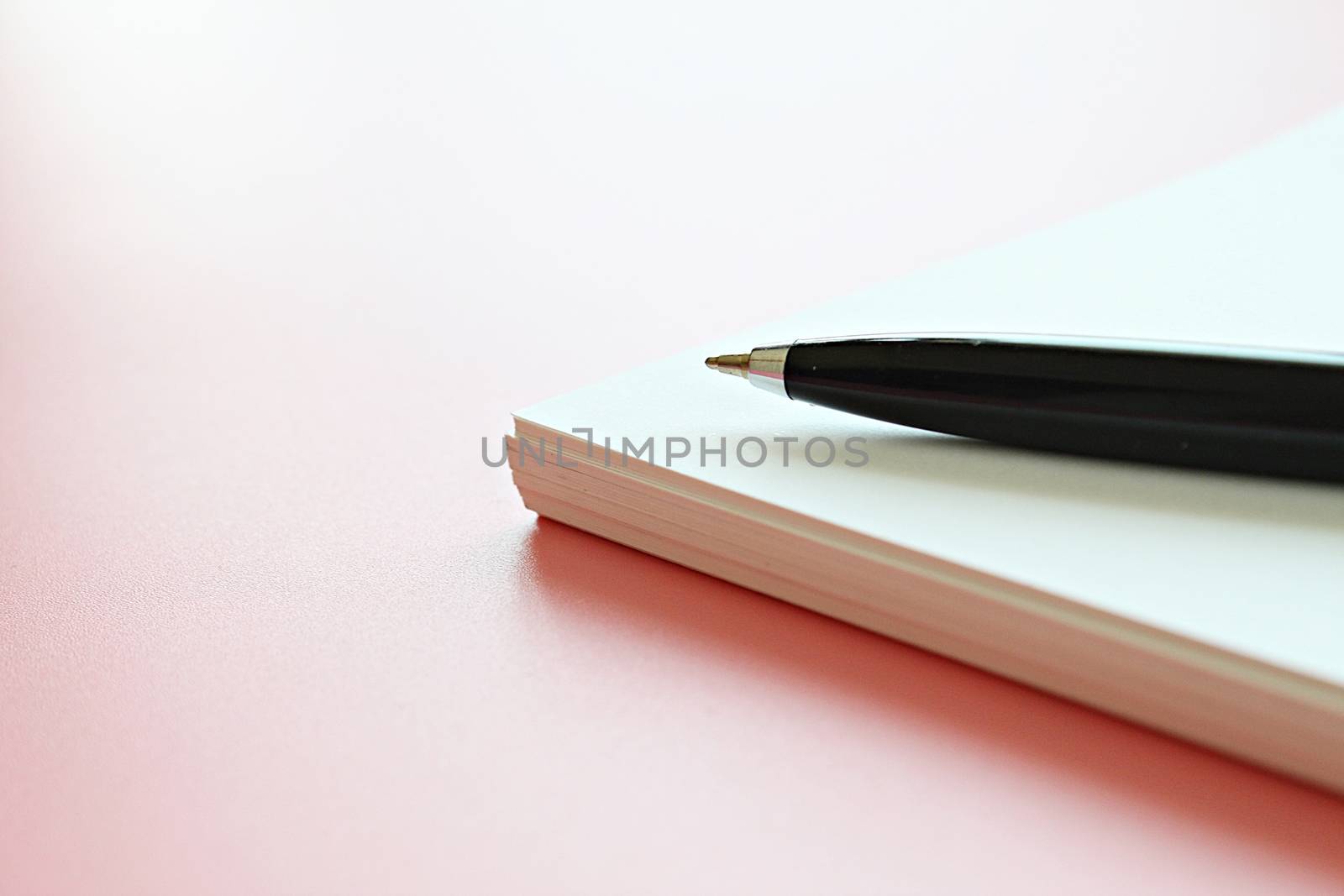 Open notebook paper and pen on pink background by sureeporn