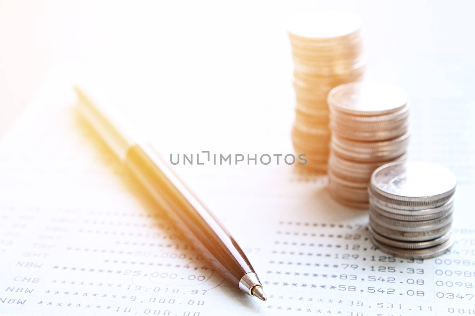 Business, finance, saving money or investment concept : Coin stacks, pen and savings account passbook or financial statement on office desk table