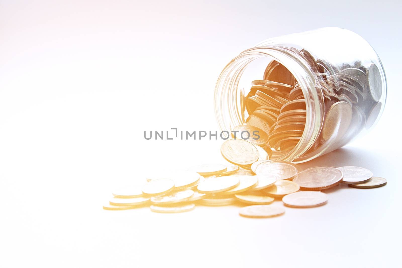 Business, finance, saving money or investment concept : Coins scattered from glass jar on white background