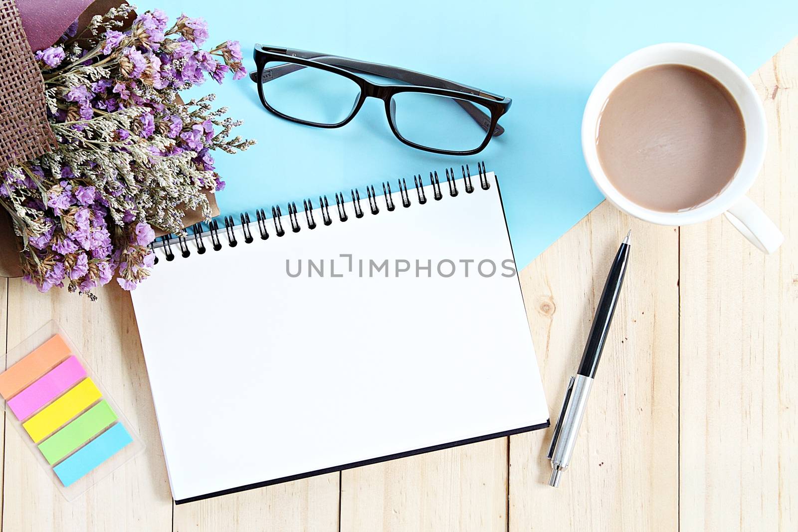 Top view or flat lay of open notebook paper, bouquet of dried wild flowers and coffee cup on desk table by sureeporn