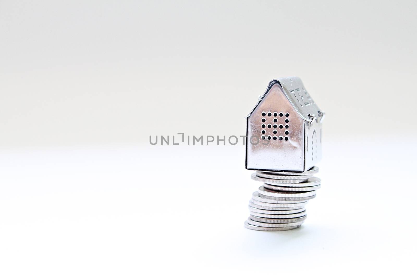 House model standing on coins stack by sureeporn