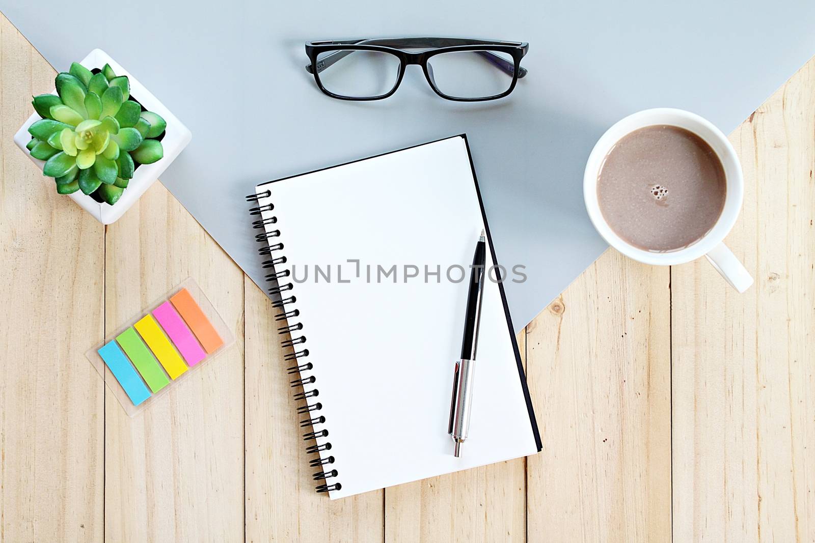Top view or flat lay of open notebook with blank pages and coffee cup on office table by sureeporn
