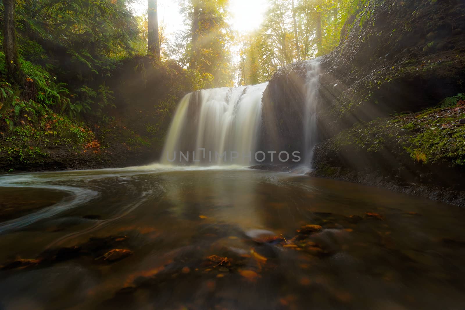 Sun rays over Hidden Falls waterfall along Rock Creek in Clackamas Oregon during Fall Season