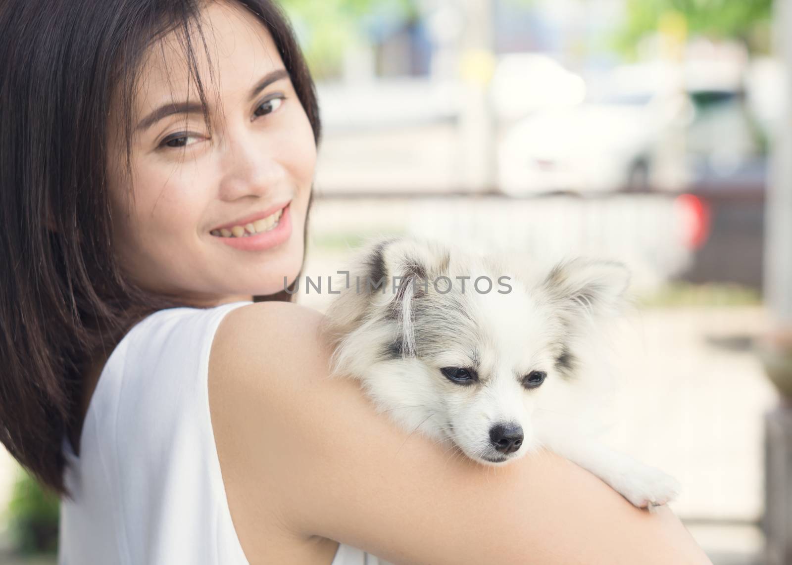 Closeup happy woman with white pomeranian dog on hand, pet health care concept with soft and selective focus