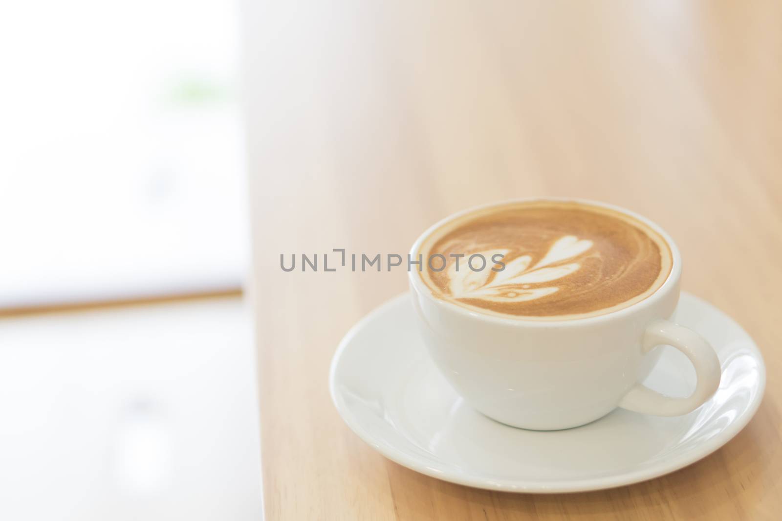 Closeup glass of latte art coffee tulip shape on wood background with vintage color, selective focus
