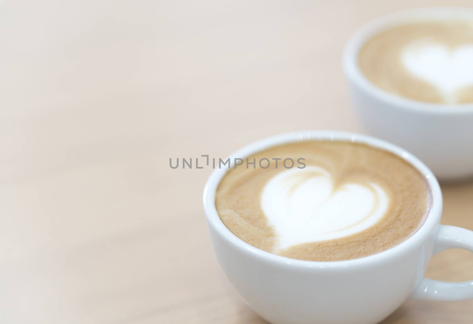 Closeup latte art coffee with heart shape in white cup for relax time and holiday concept, selective and soft focus 