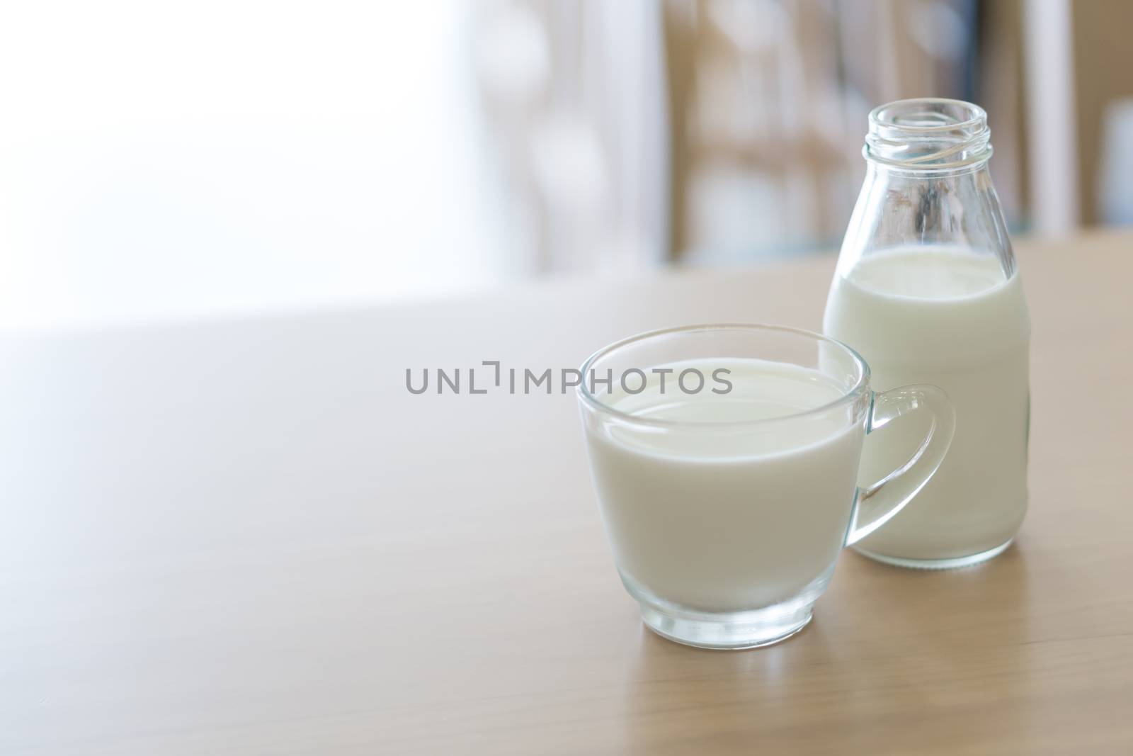 Closeup glass and bottle of millk on wood table background for healthy drink concept, selective and soft focus