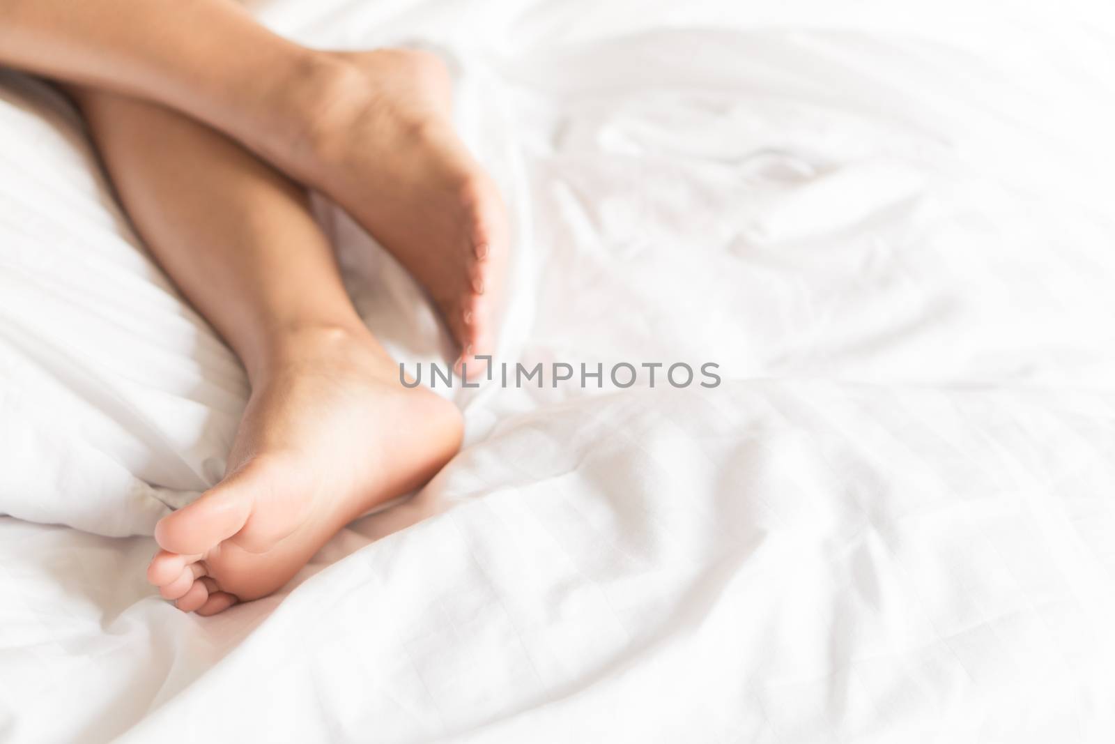 Closeup woman feet relaxing and happy time on white bed, beauty and health care concept