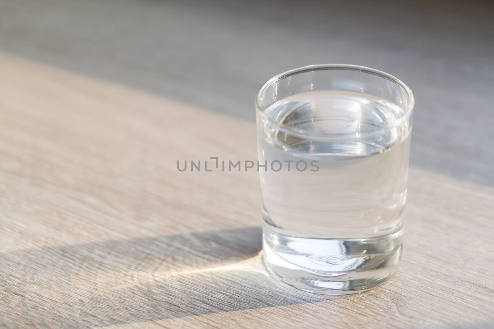 Glass of water on wood table with light in the morning, healthy care concept, selective focus