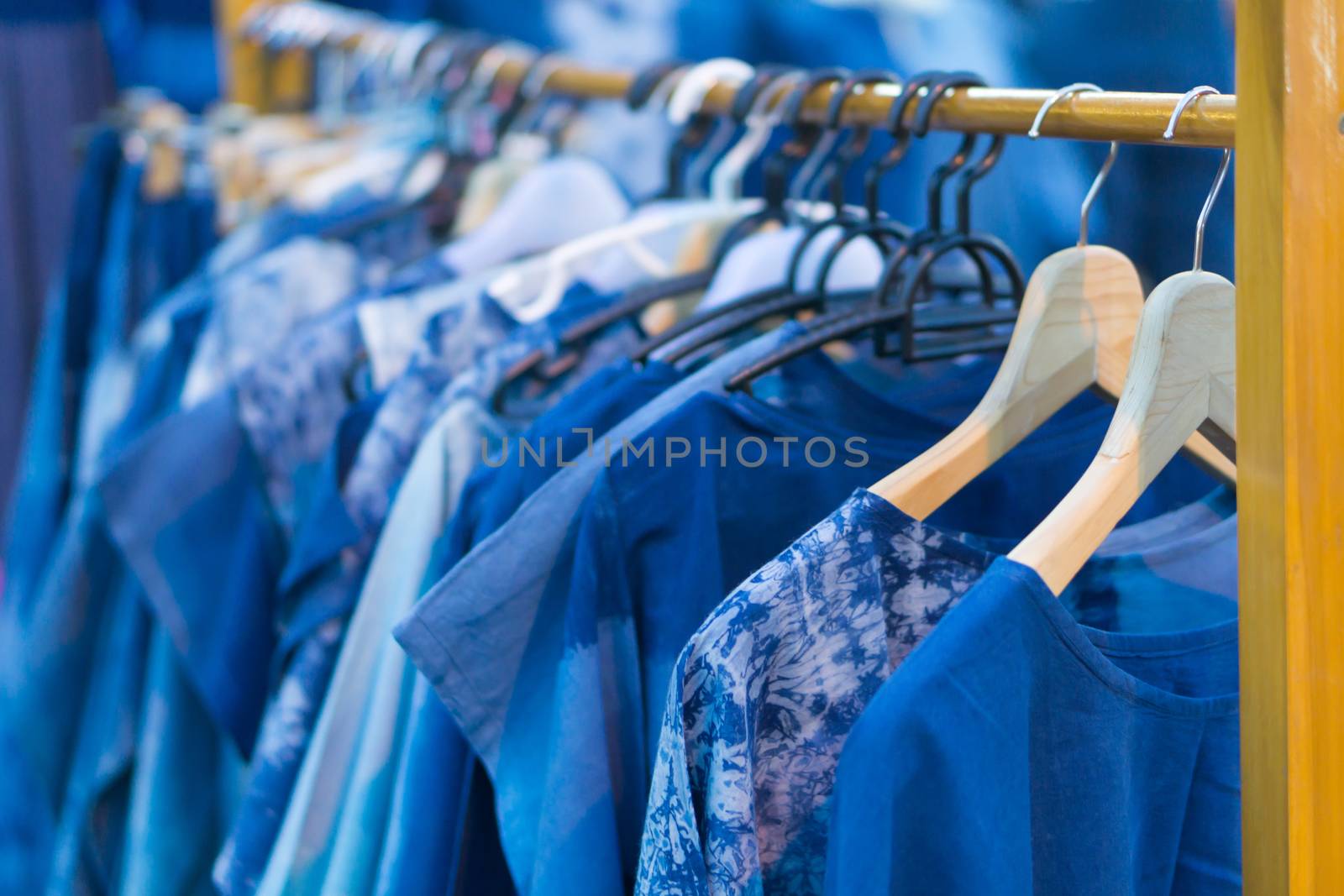 Closeup white and blue T-shirt in clothes rack at walking street, selective focus