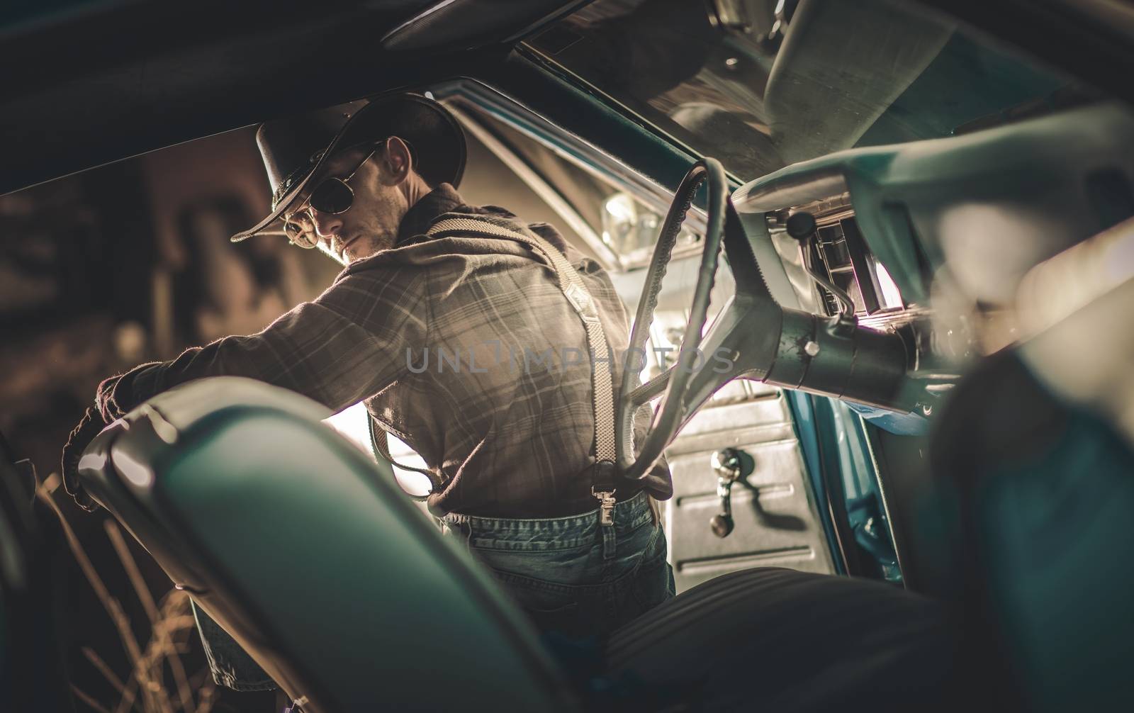 American Caucasian Cowboy Driver in His 30s Wearing Western Clothes and Sunglasses Seating Inside American Classic Muscle Car. American Countryside Theme.