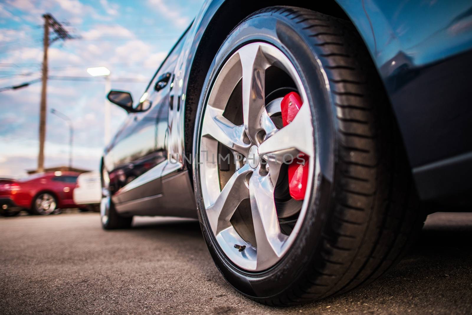 Car on the Parking Spot. Alloy Wheel Closeup Photo. Lower Ground Level. Transportation and Automotive Theme.