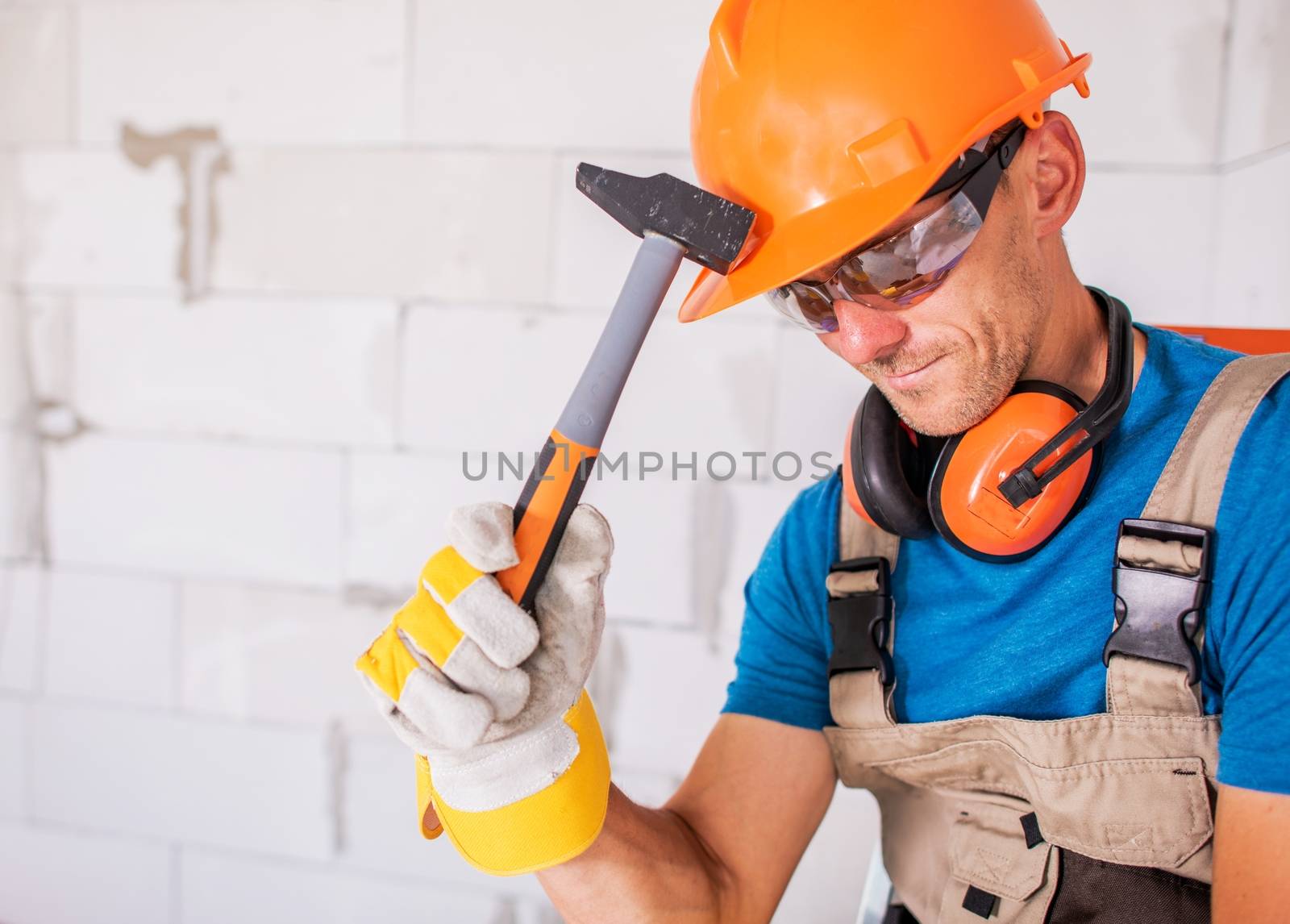 Construction Worker Theme. Caucasian Builder with Hammer Wearing Safety Equipment. Construction Zone.