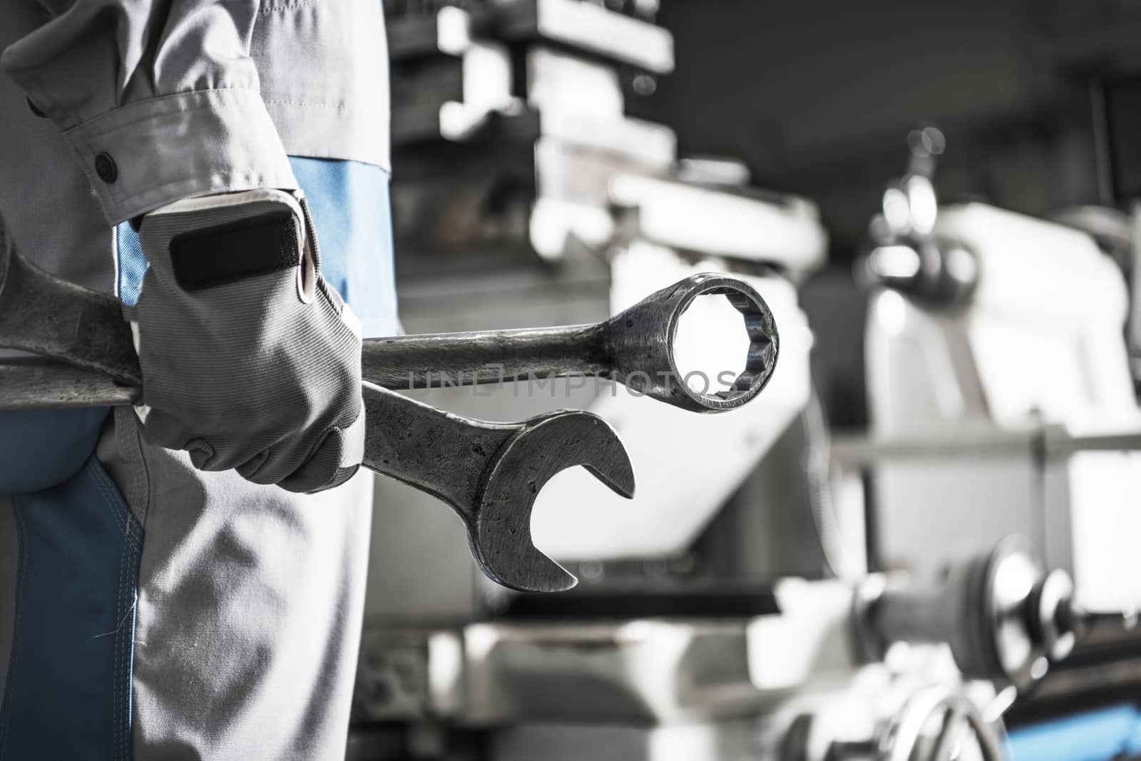 Metalworking Mechanic with Big Wrenches Preparing Himself For the Big Fix of Industrial Grade Lathe Machine.