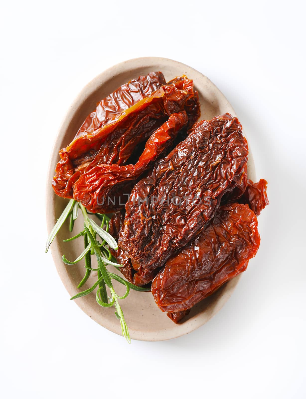 plate of sun dried tomatoes with rosemary on white background
